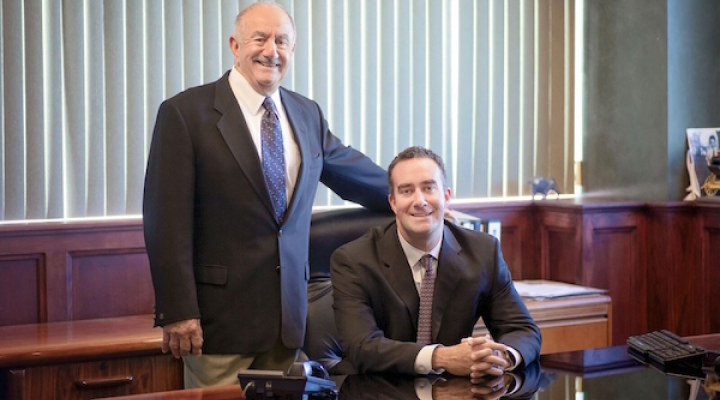 Sam Eyde Sr stands with Sam Eyde II next to a desk in an office